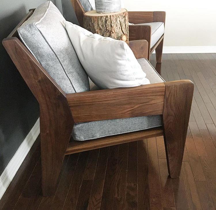 A pair of solid walnut armchairs with grey tweed cushions.  Side view . 