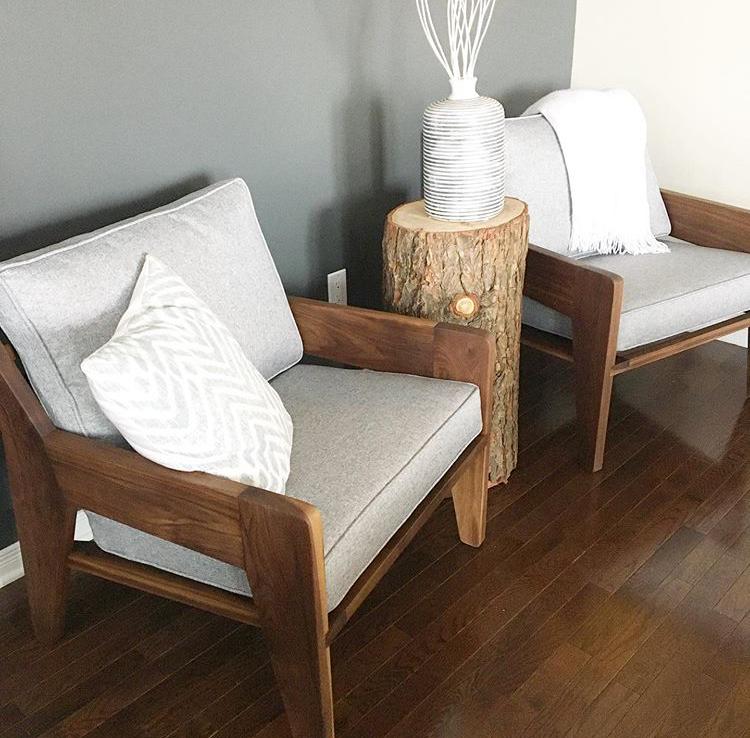 A pair of solid walnut armchairs with grey tweed cushions.  Shown with a decorative throw and an accent pillow.  