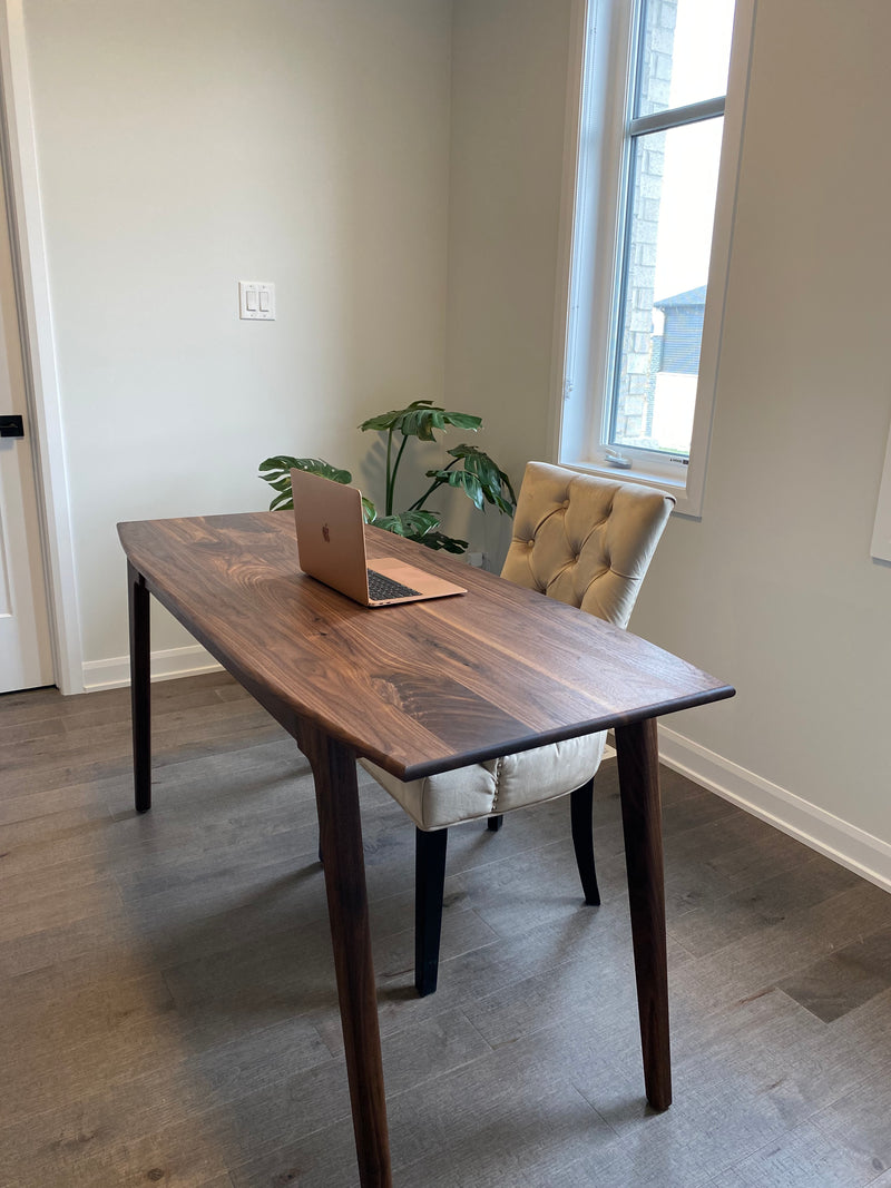 Solid walnut desk with a hidden drawer and tapered legs in a natural finish