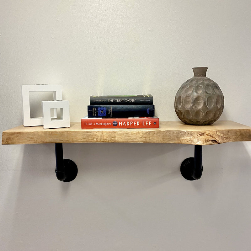 Natural edge solid wood shelf with books and decor and black pipe brackets