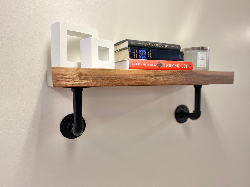 solid wood shelf with black pipe brackets with books and decor