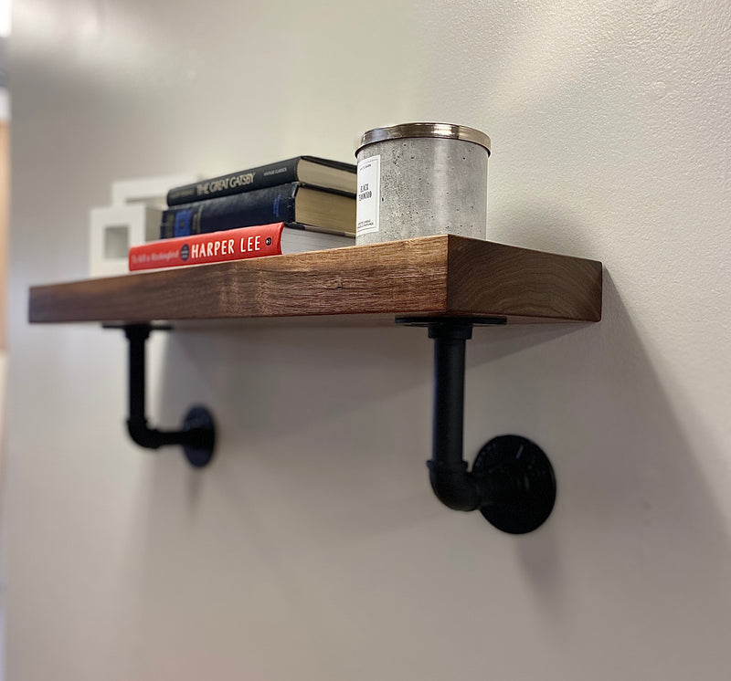 solid wood shelf with black pipe brackets with books and decor